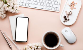 Overhead image of wedding flowers and accessories on a remote worker's desk.