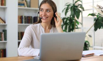A remote dispatcher working from her home office on a laptop and using a headset for remote dispatcher jobs