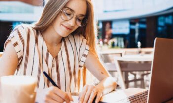 A woman working remotely from a cafe on a laptop outside.