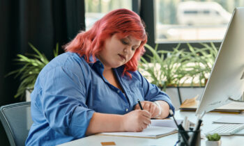 A woman with pink hair writing a business plan for a business that costs no money