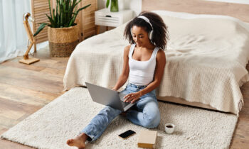 A young female wearing headphones looking at her laptop, reading an article on the best fiverr jobs