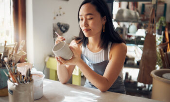 A young woman painting a coffee mug to sell online