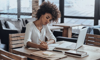 A young woman writing in a notebook looking for online jobs for writers