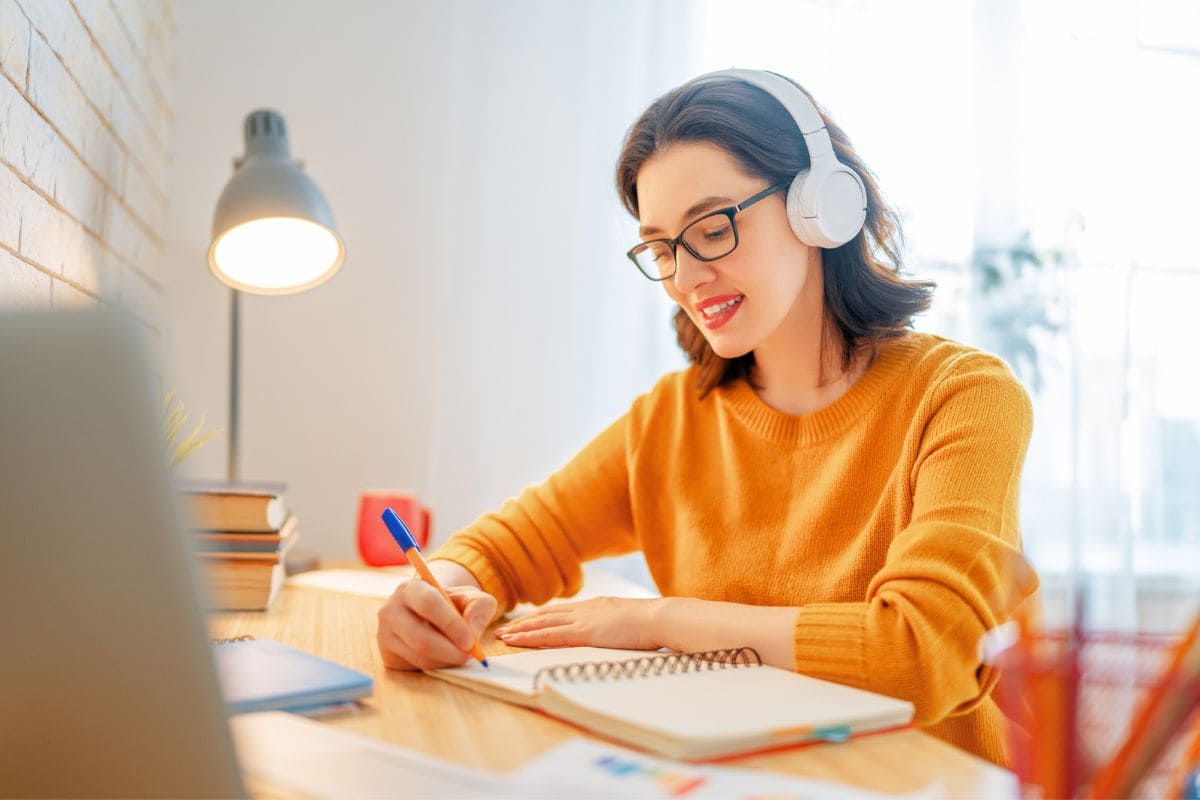 Woman working at home and writing in a notebook at a desk for blog post no interview jobs