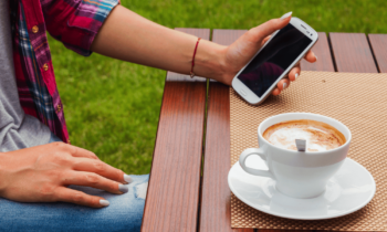 Woman taking paid surveys on her mobile phone drinking a latte